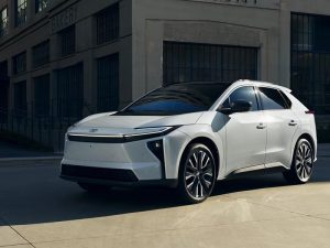 Un SUV eléctrico Toyota bZ de 2026, de color blanco, aparcado cerca de un edificio.